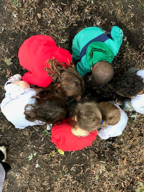 Children gathered in a circle looking down at the ground