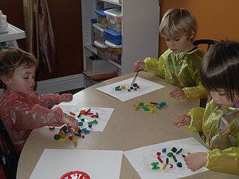 Three children playing with colorful clay at a table