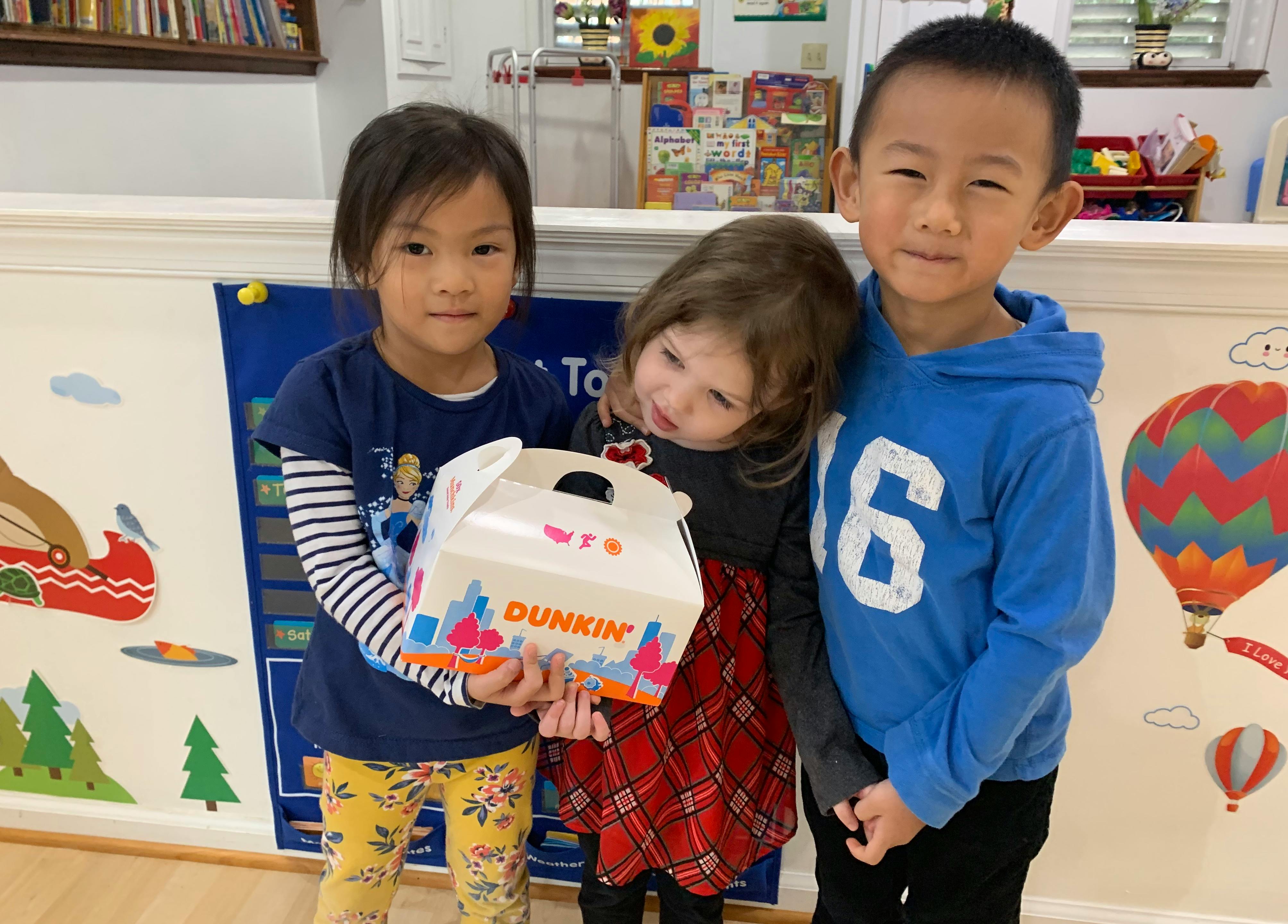 Three children holding a Dunkin' box