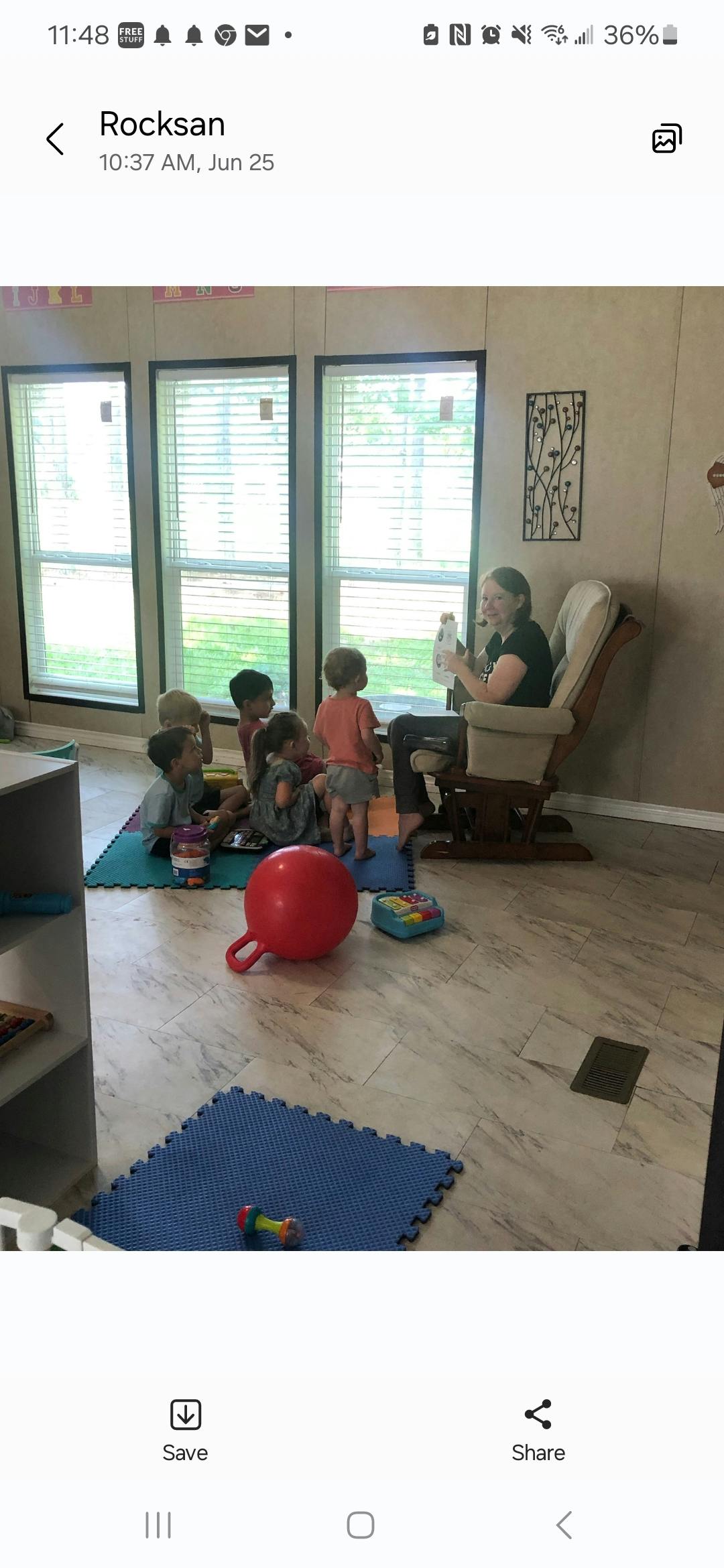 Adult sitting in a chair with several children gathered around on the floor