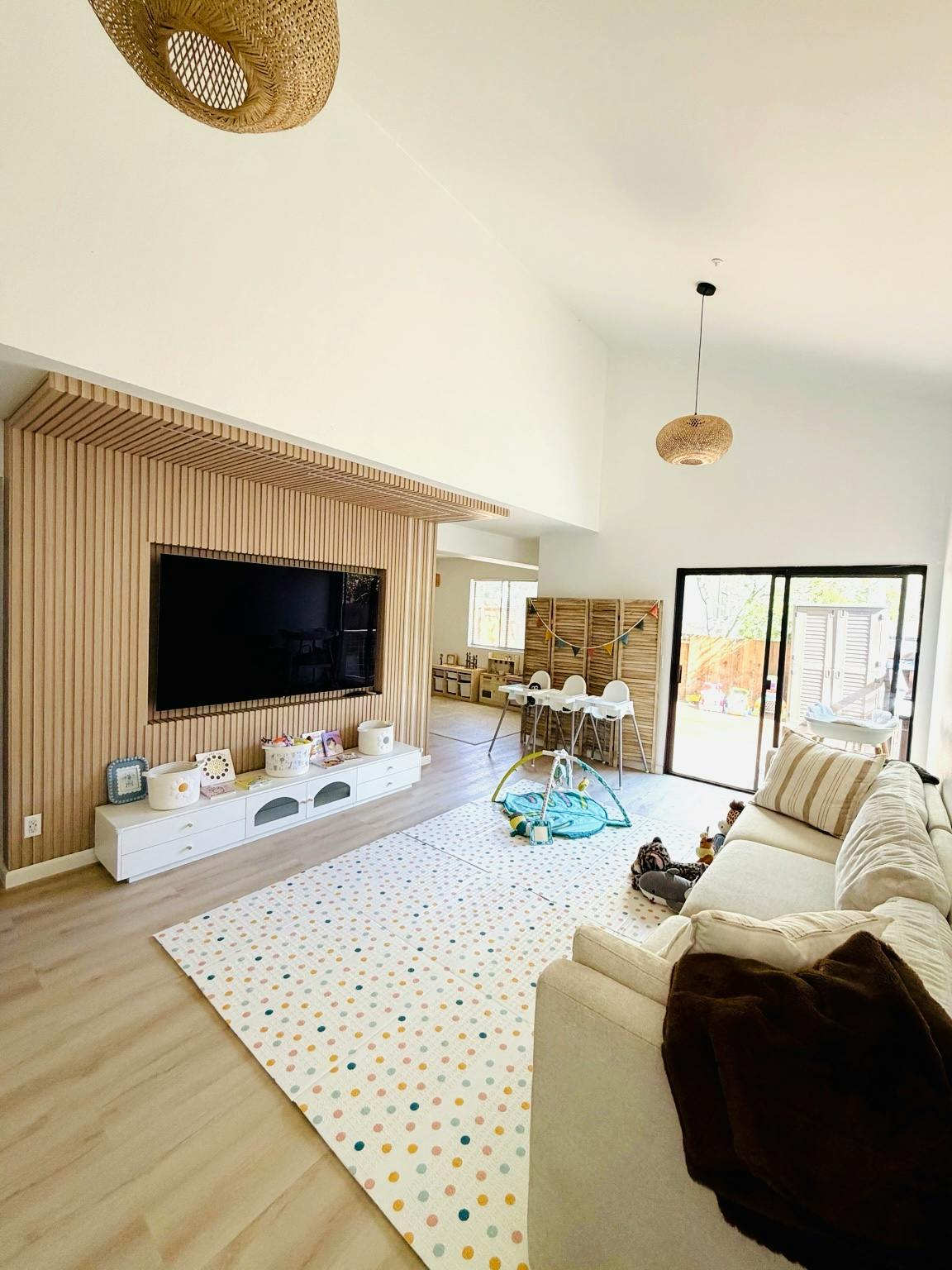 Living room with TV, couch, playmat, and baby high chairs