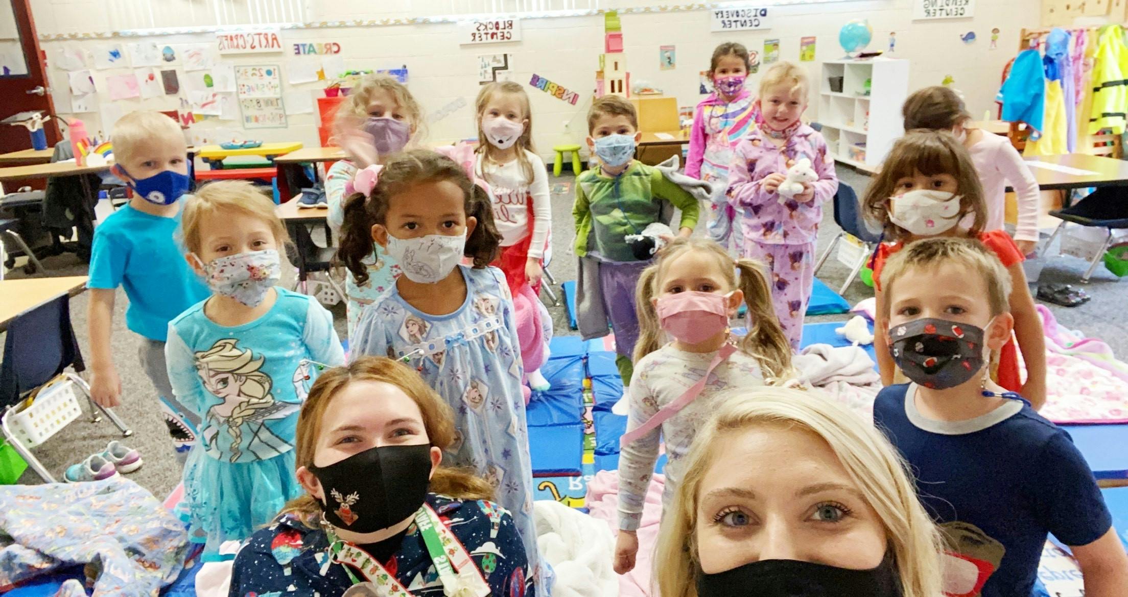 Group of children and adults wearing masks in a classroom