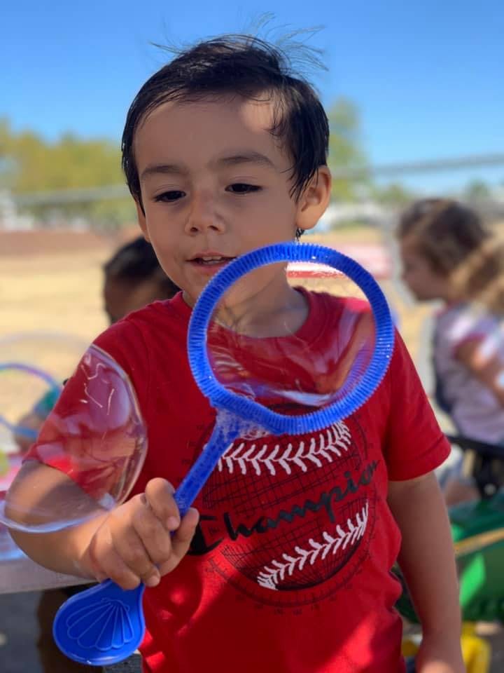 Child holding a blue bubble wand with bubbles