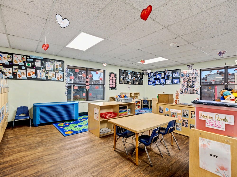 Empty classroom with small tables and chairs, artwork on walls