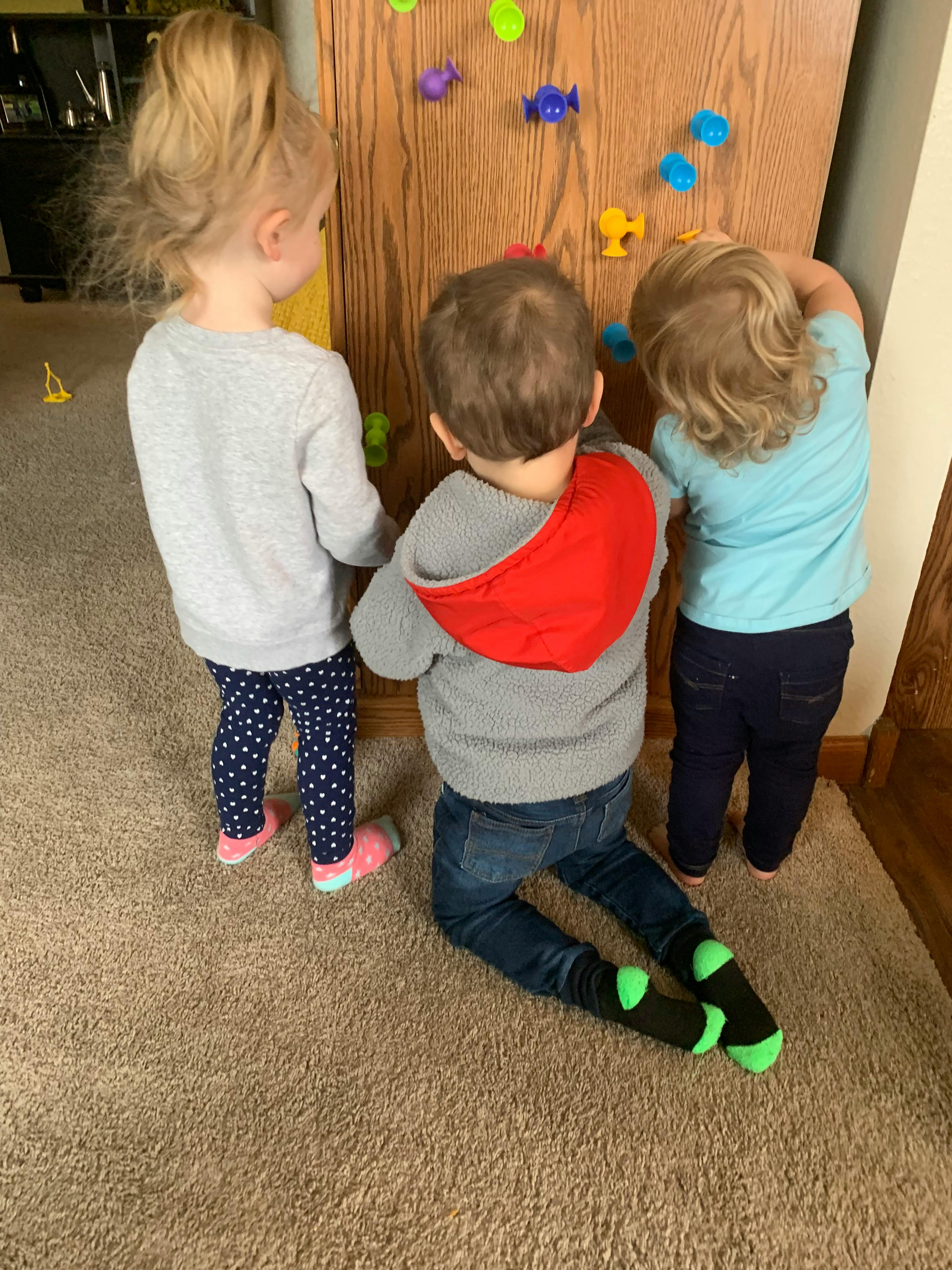 Three children playing with toys on a wooden board