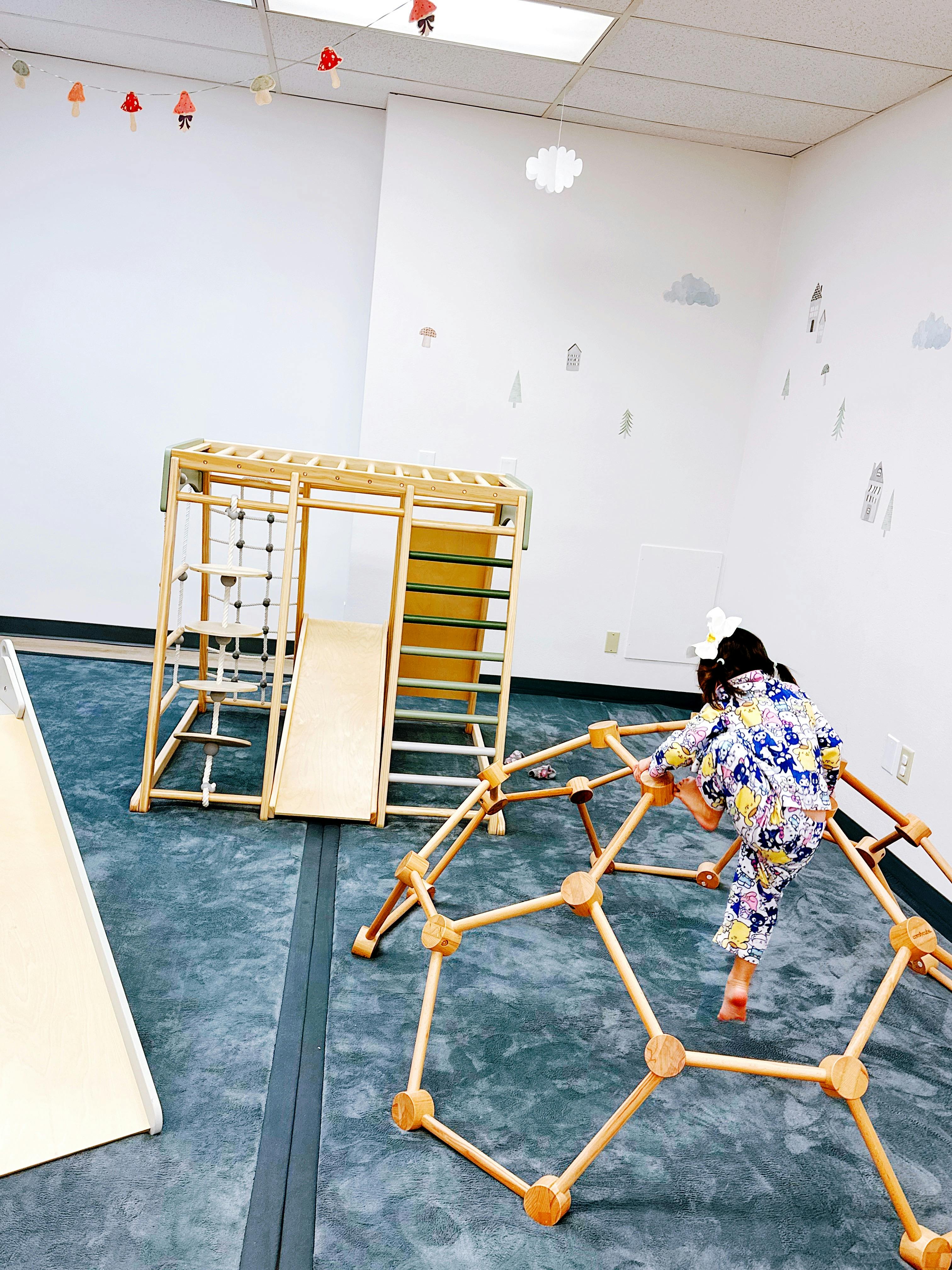 Child climbing a wooden geodesic dome in an indoor play area