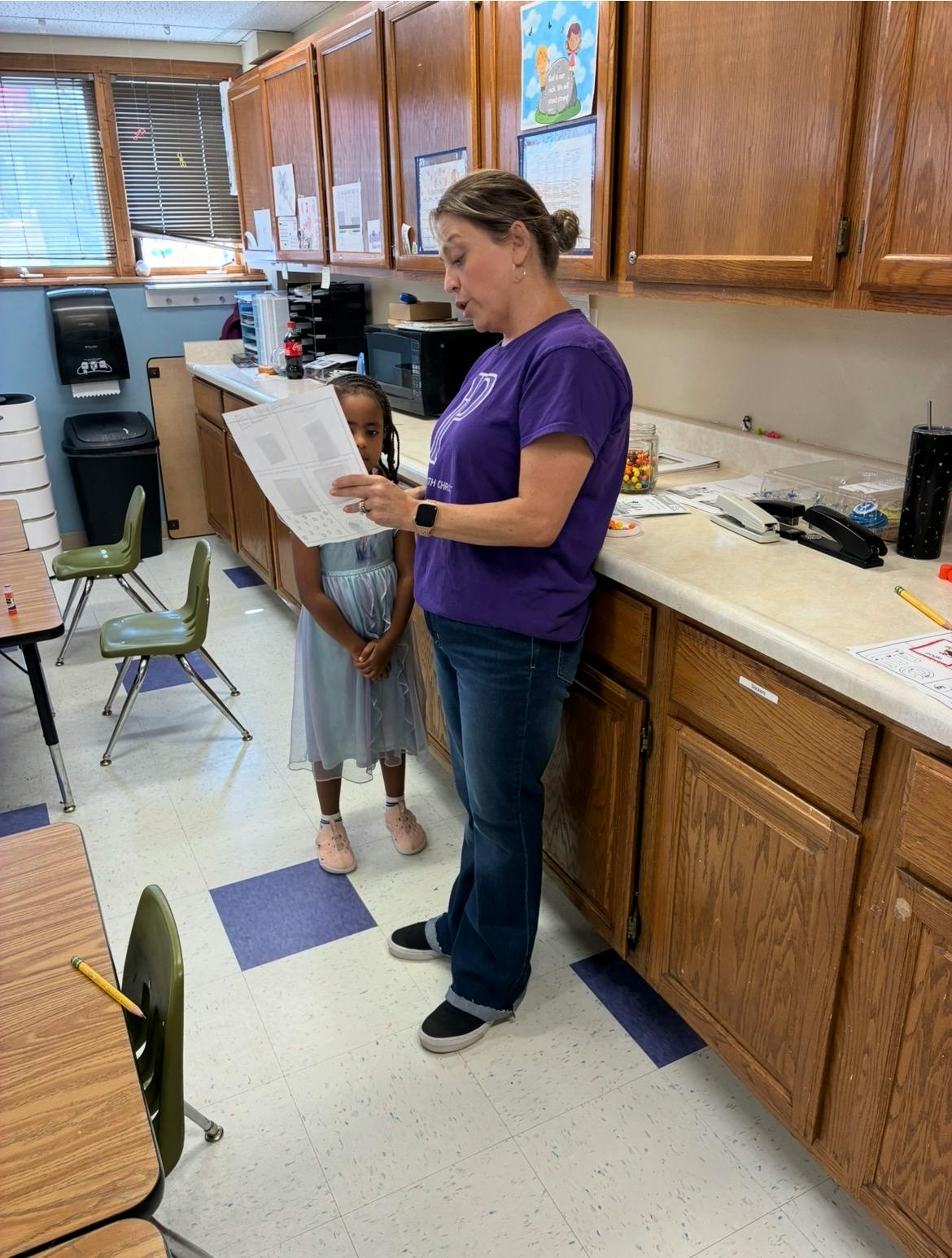 Adult and child looking at a paper together in a classroom