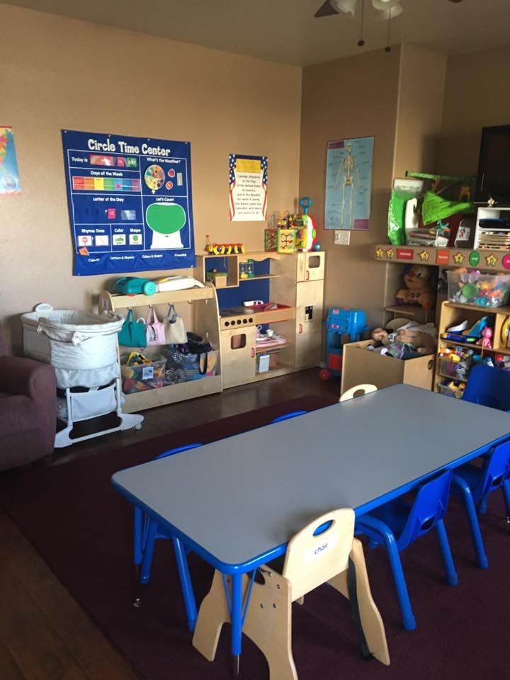 Classroom with a long table and chairs, play kitchen, and wall charts