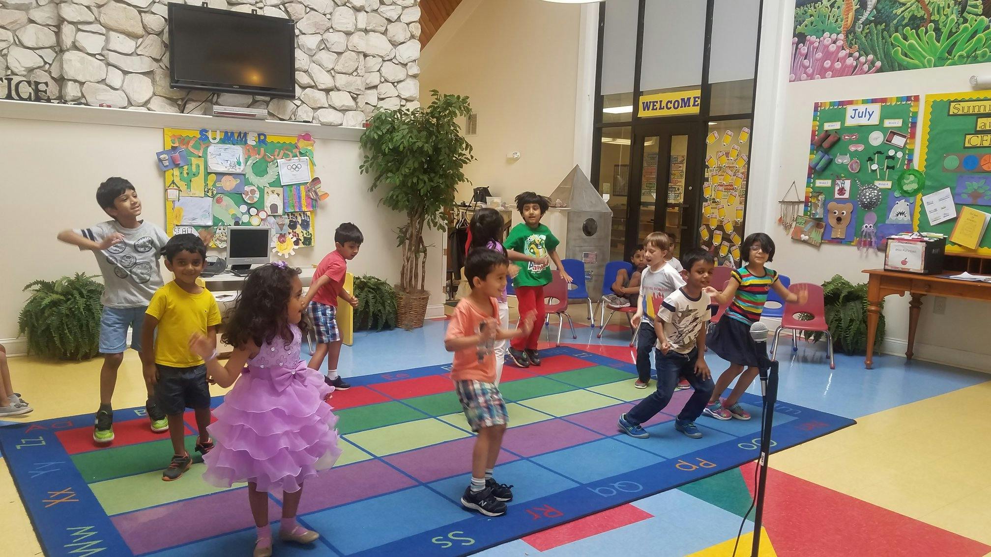Children dancing on a colorful mat in a large room