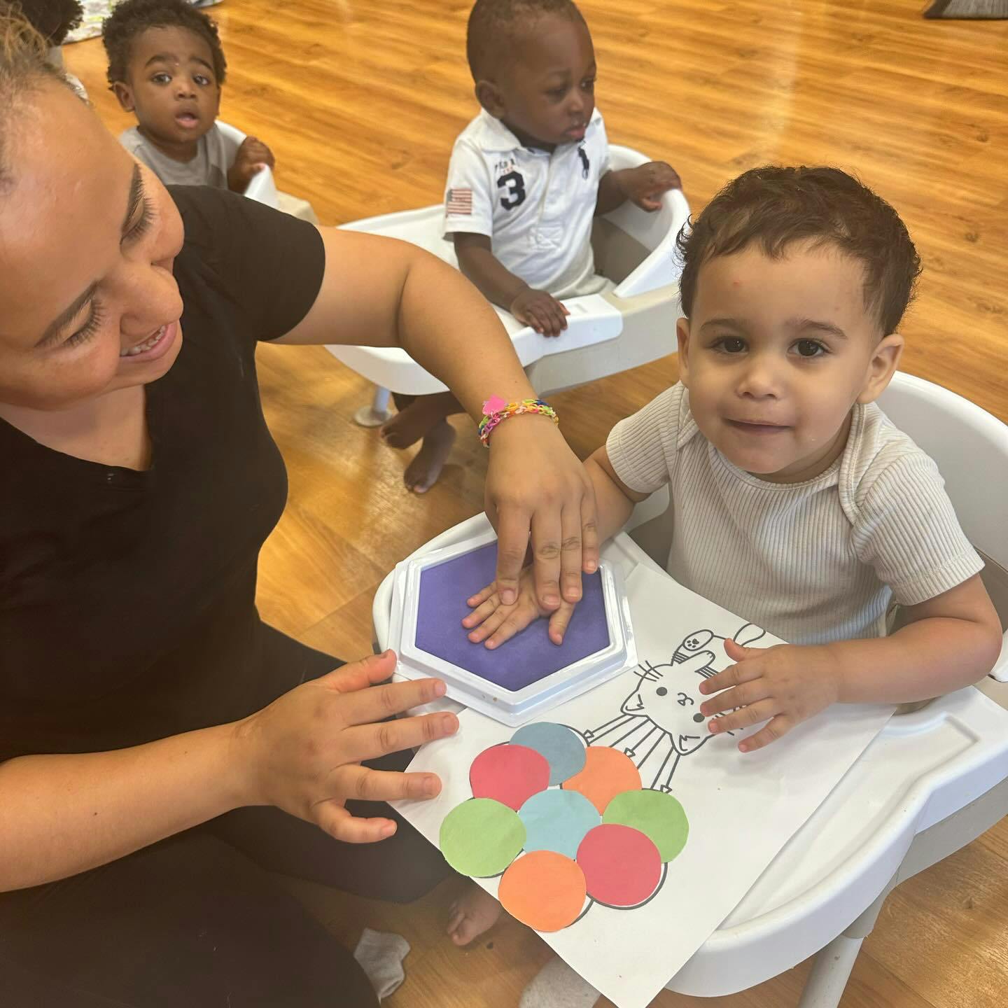 Person helping a child make a handprint with purple ink
