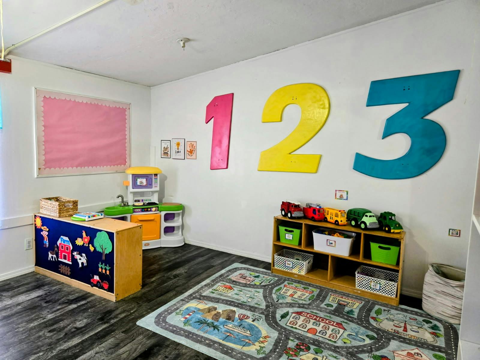 Playroom with number cutouts on the wall, toy kitchen, and road play rug