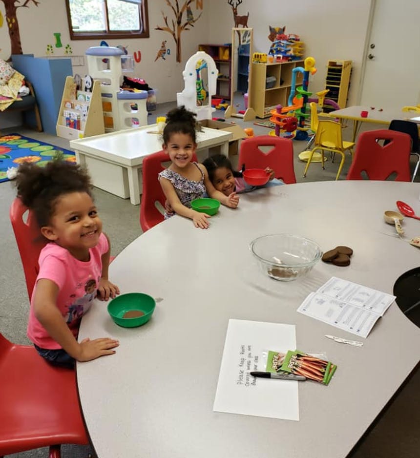 Three children sitting at a table in a classroom