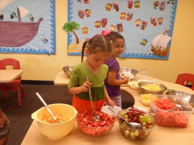 Two children preparing fruit salad in a classroom