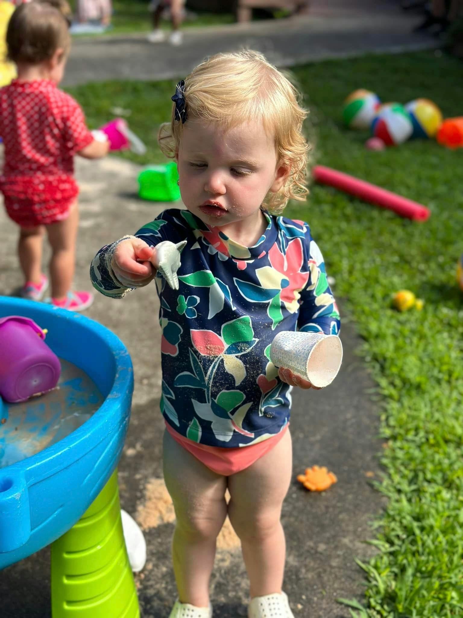 Child playing with a toy and a cup outdoors