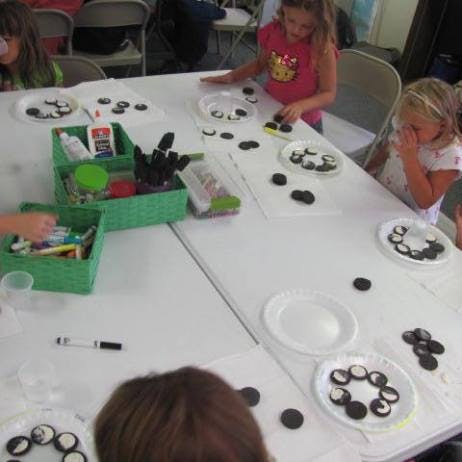 Children at a table with craft supplies and cookies