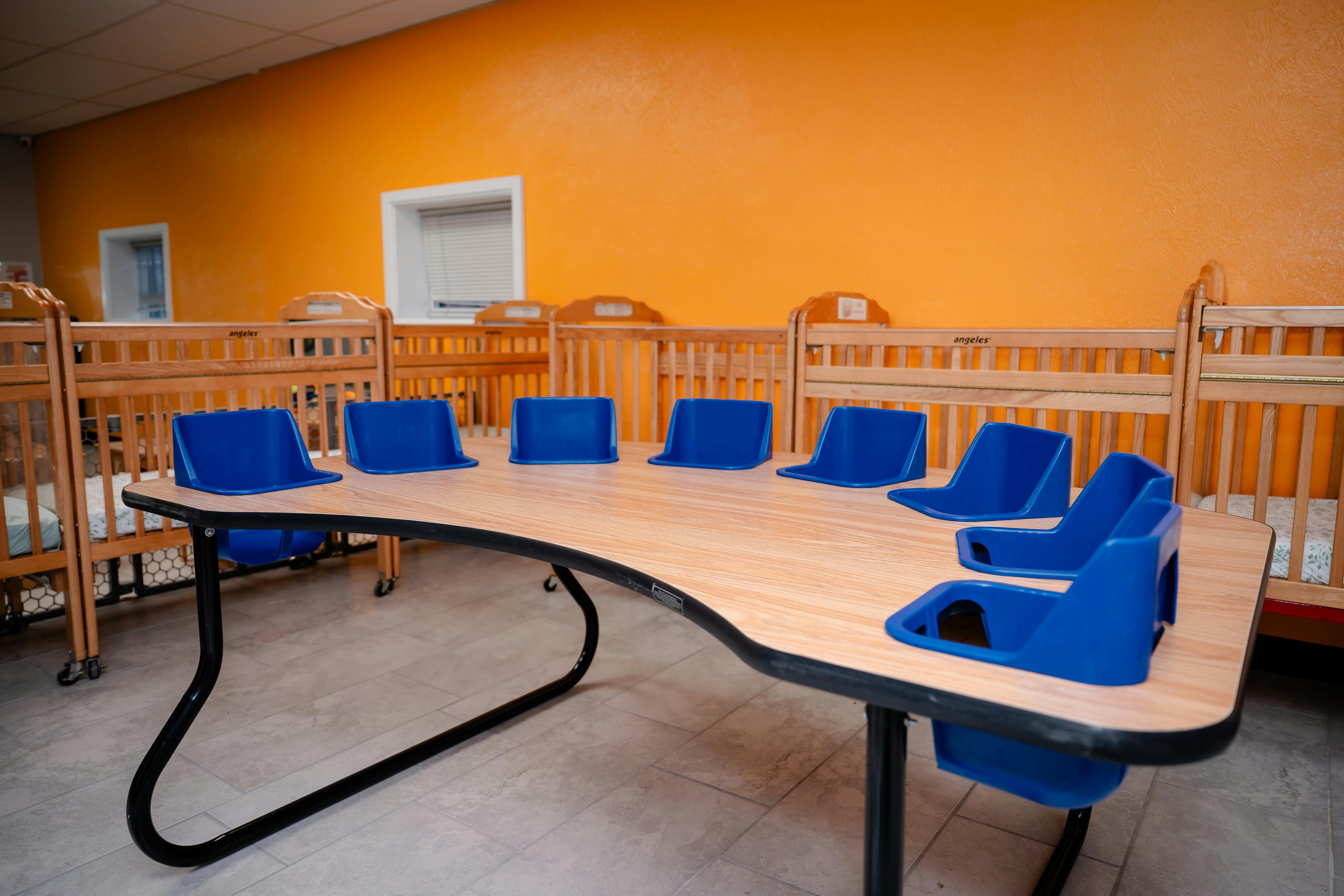 Table with blue child seats in a room with cribs