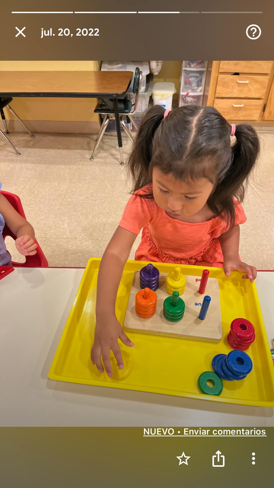 Child playing with a ring stacker toy on a tray