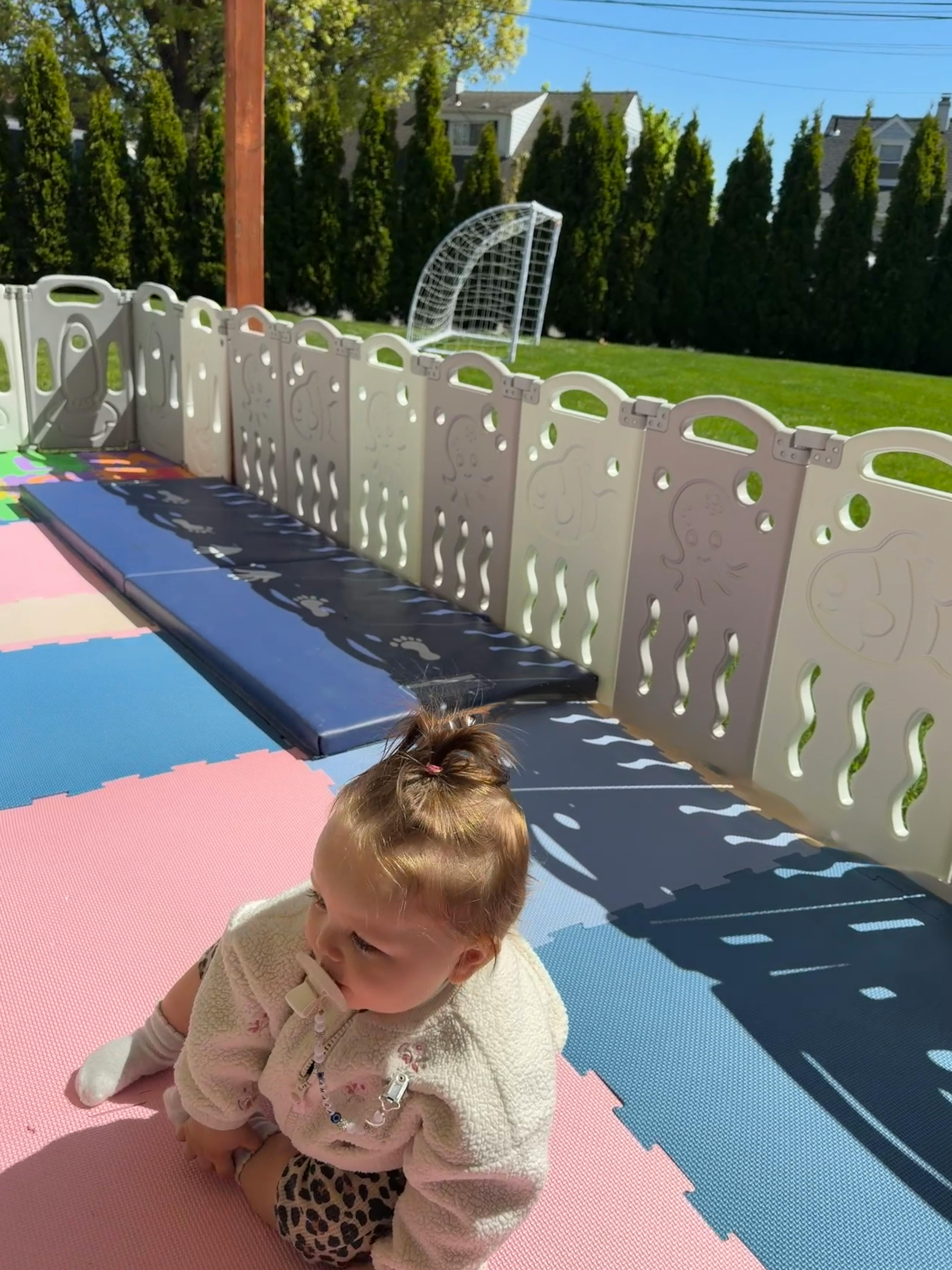 Child sitting on a play mat with a pacifier