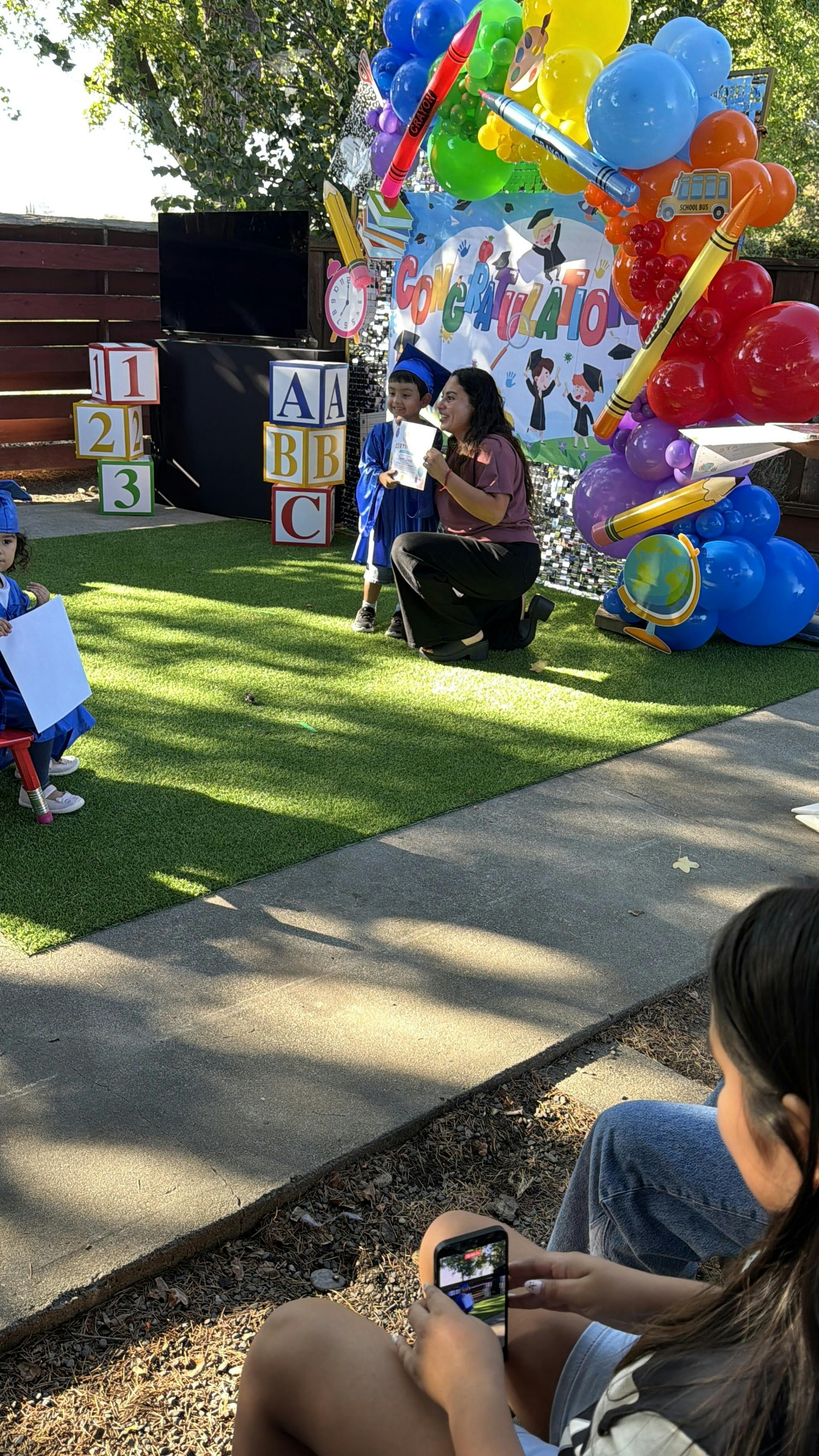 Adult handing a certificate to a child in a graduation cap