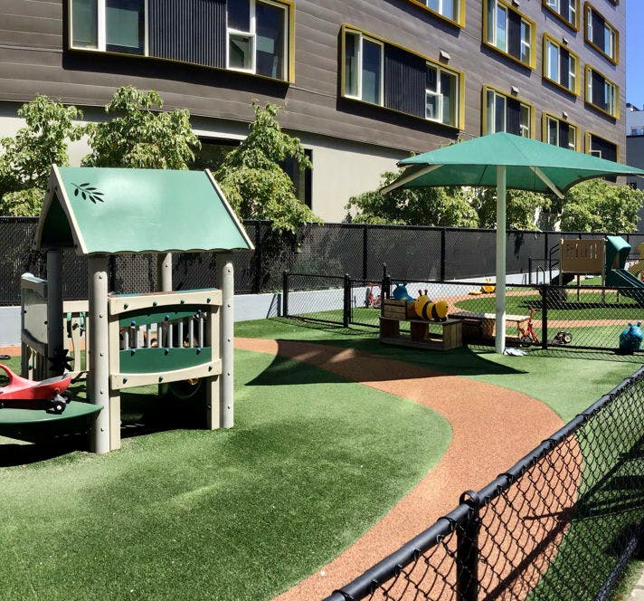 Playground with play structure, green umbrella, and artificial turf