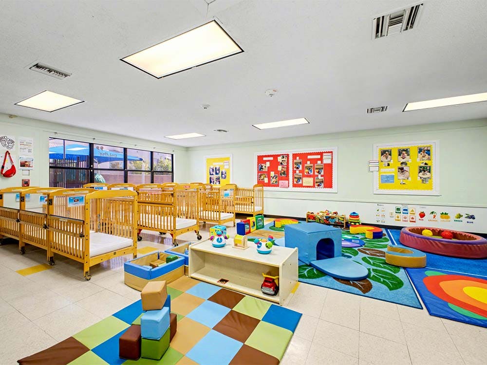 Cribs and play area with toys in a brightly lit room
