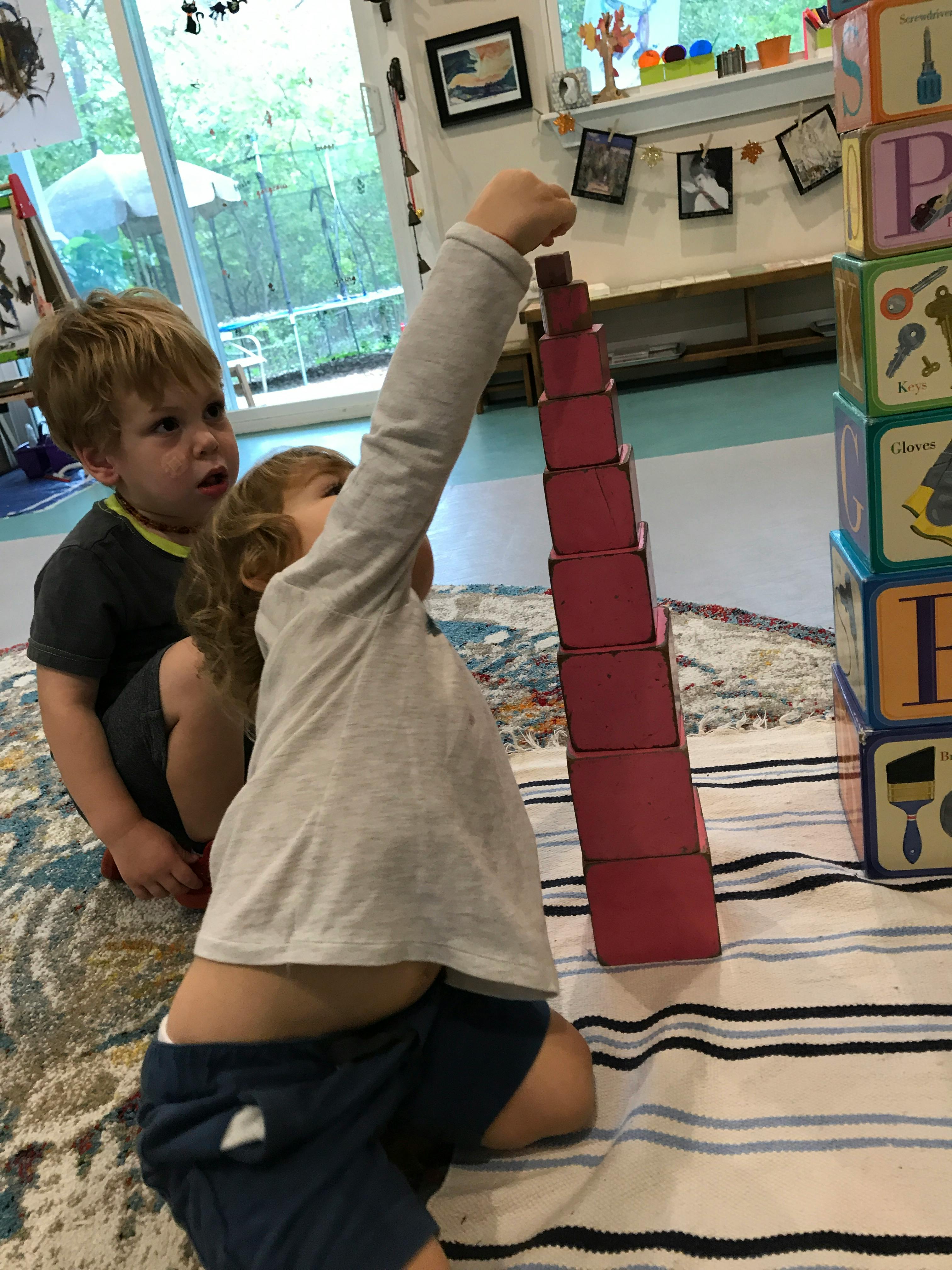 Two children playing with stacking blocks in a classroom
