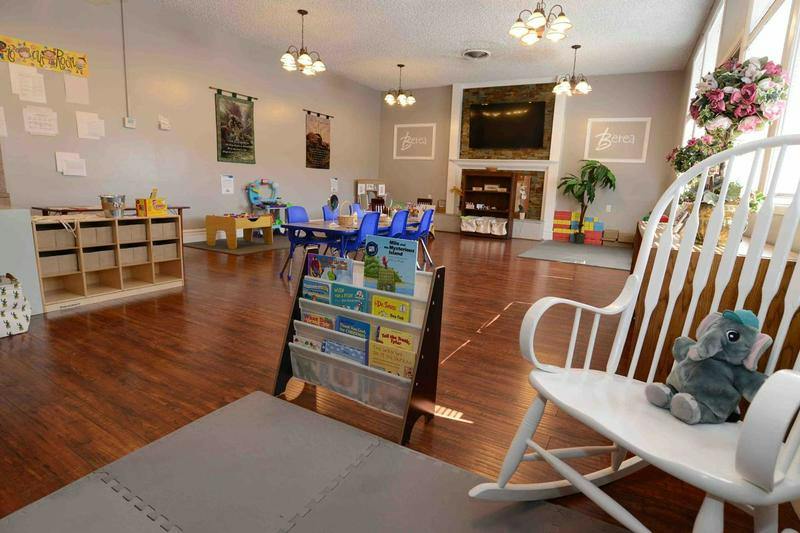 Childcare room with a rocking chair, book display, and tables