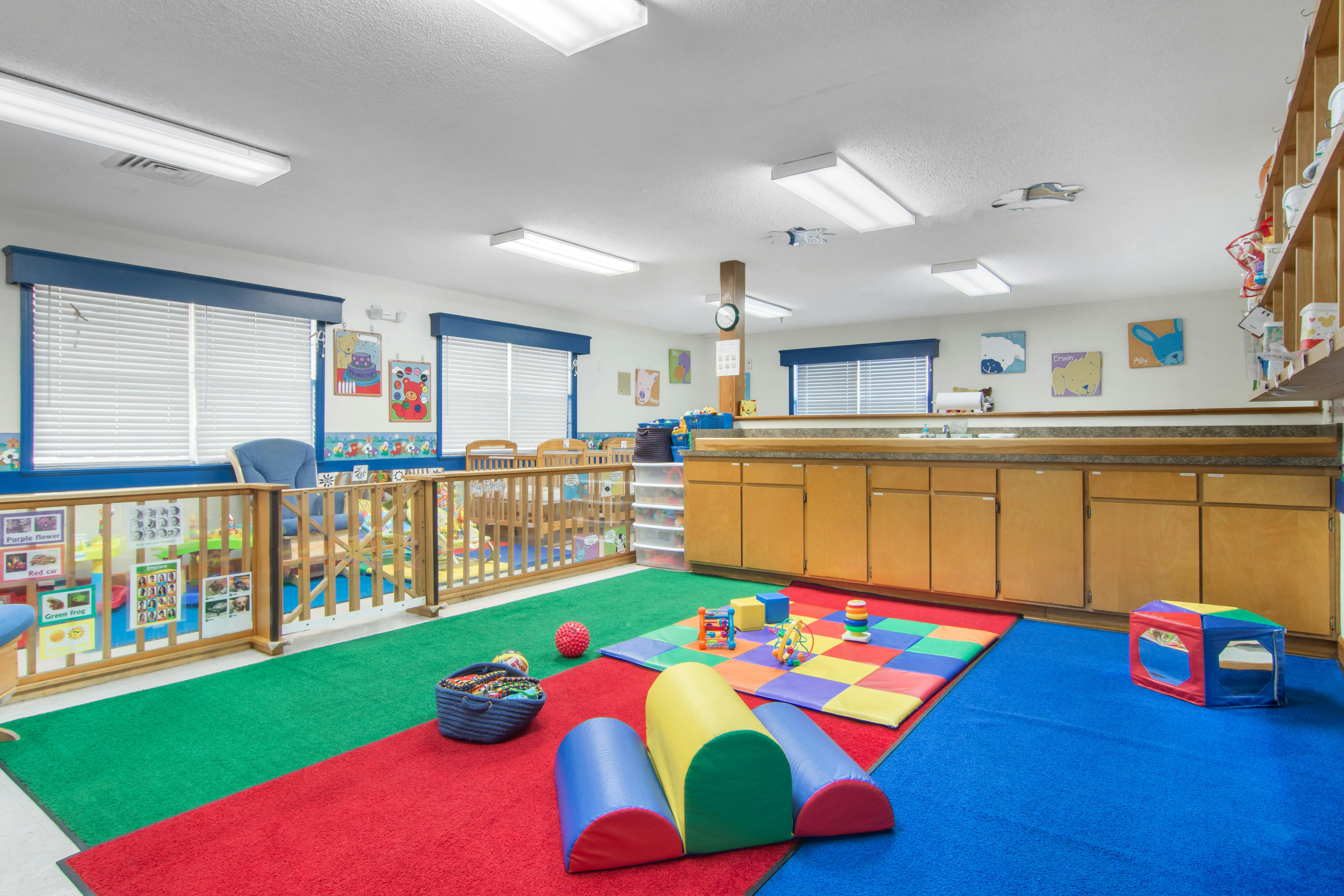 Children's play area with colorful carpet, toys, and small wooden fence