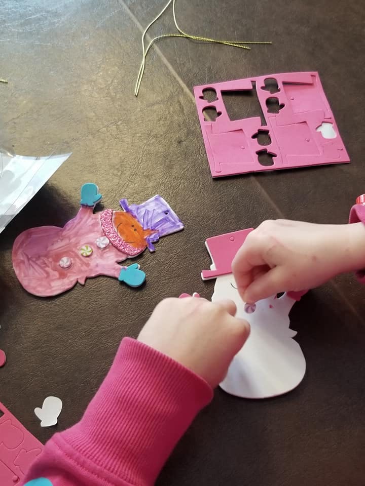 Child's hands decorating a snowman cutout