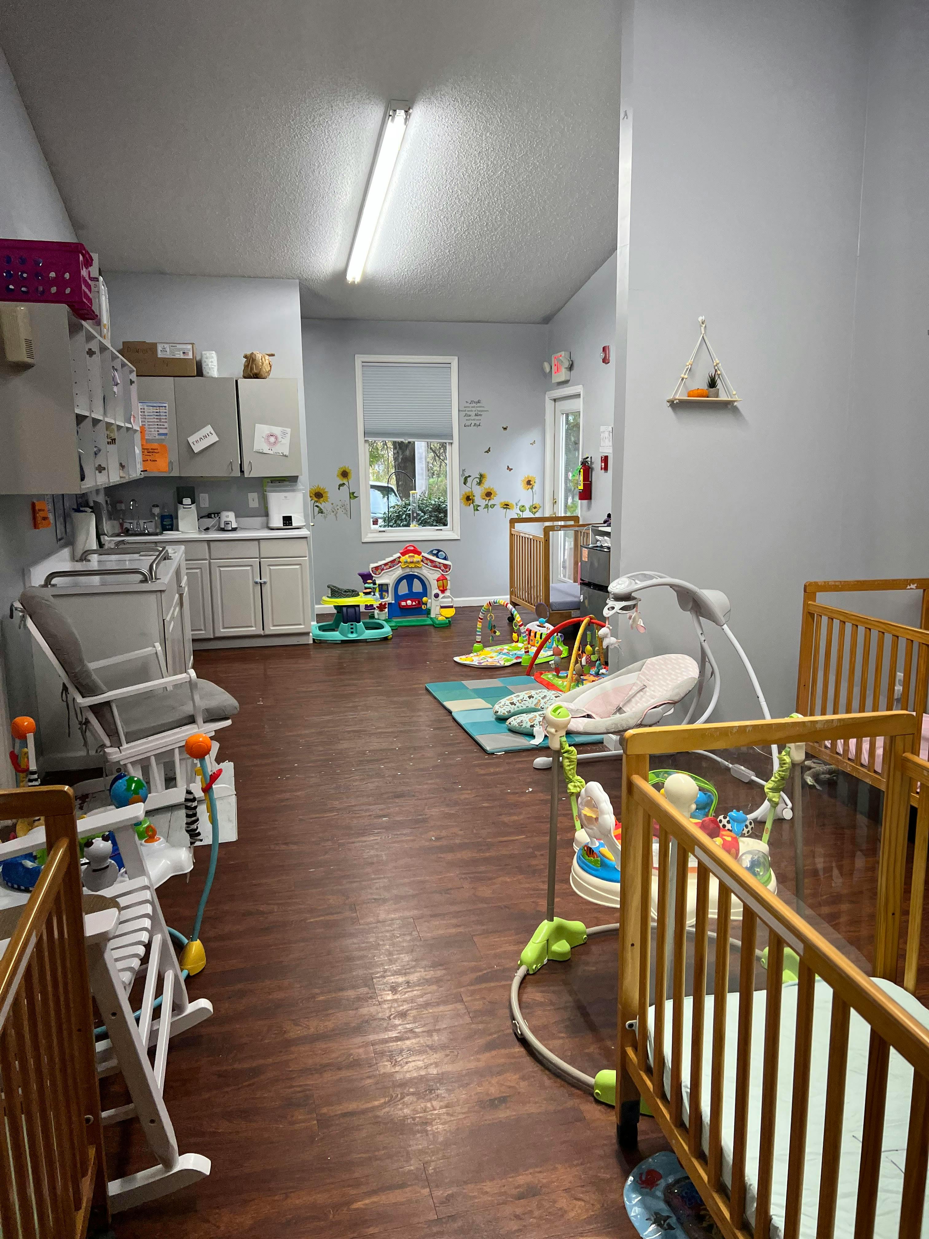 Nursery room with multiple cribs and baby play equipment