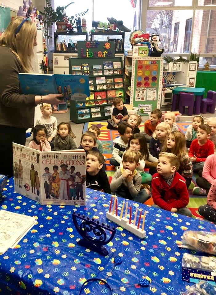 Person reading a book to a group of children in a classroom