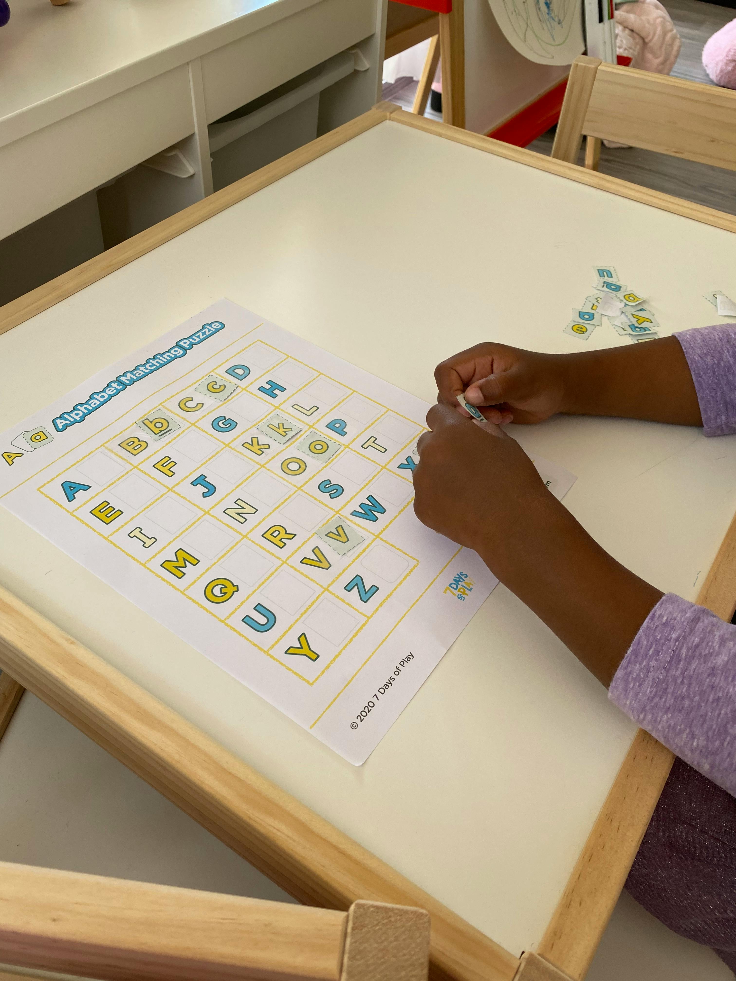 Child's hands working on an alphabet matching puzzle on a table