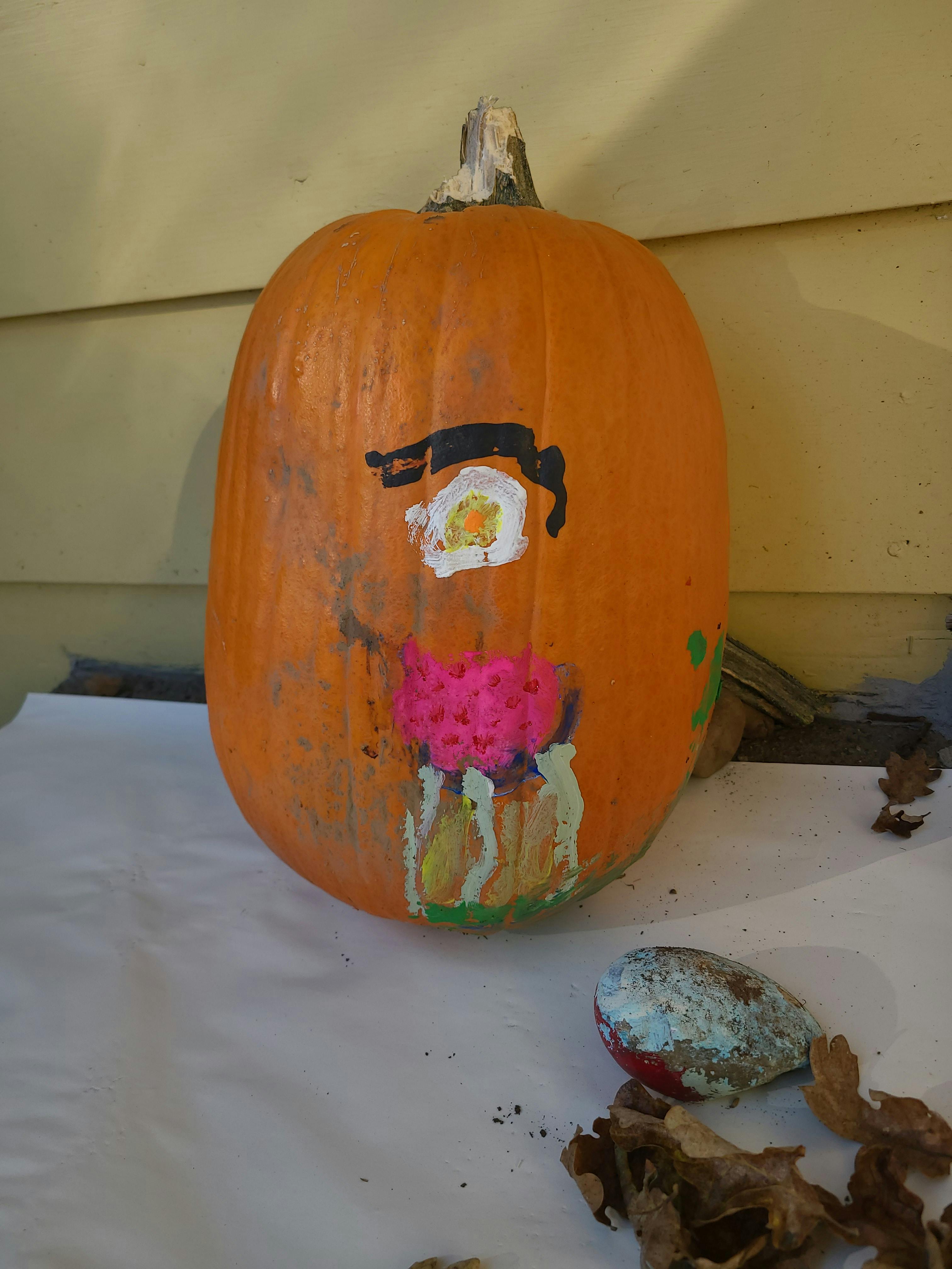 Pumpkin with painted face, one eye and pink mouth