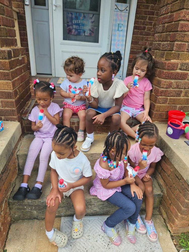Group of children eating popsicles on front porch steps