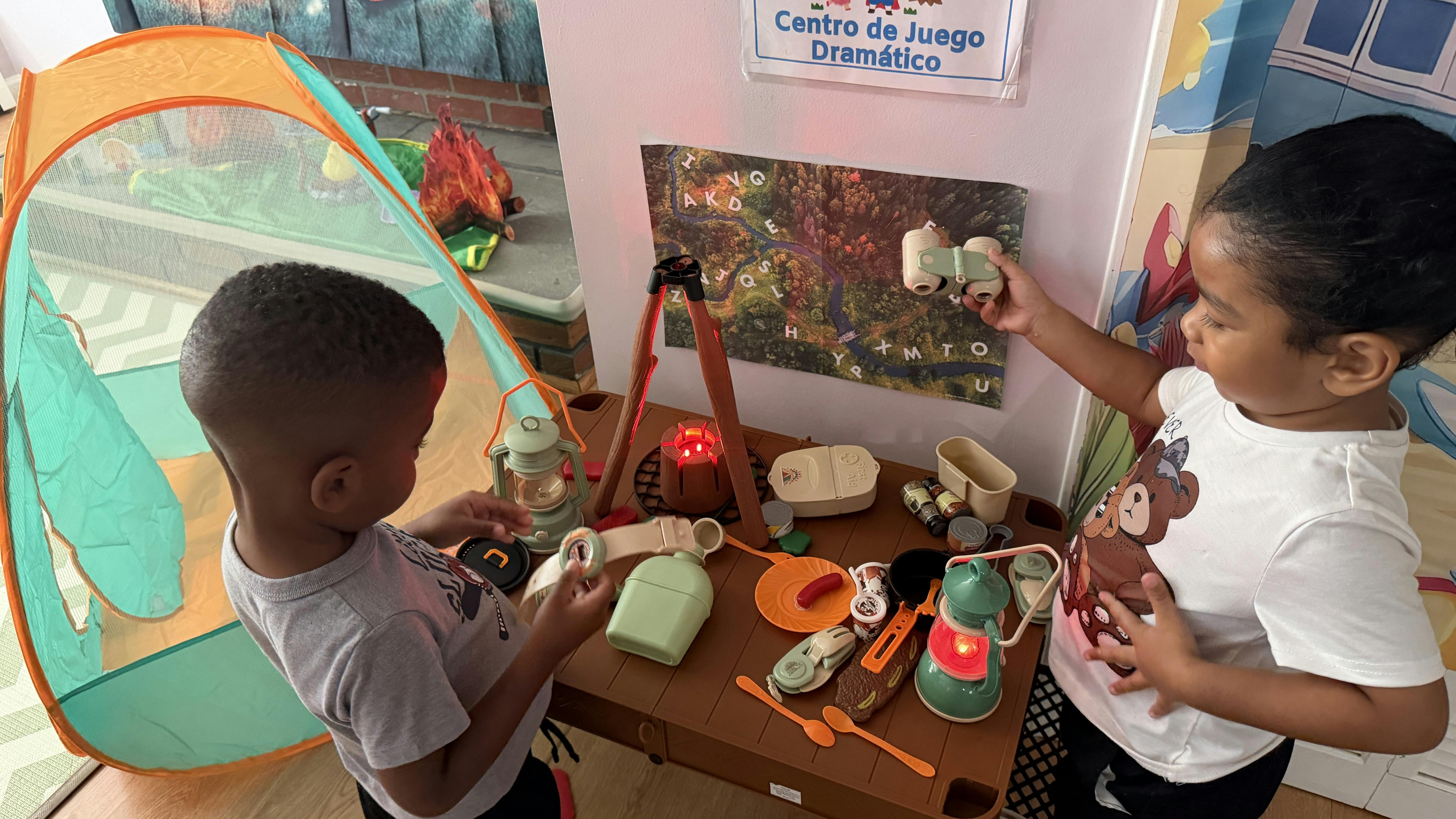 Two children playing with camping themed toys in a classroom