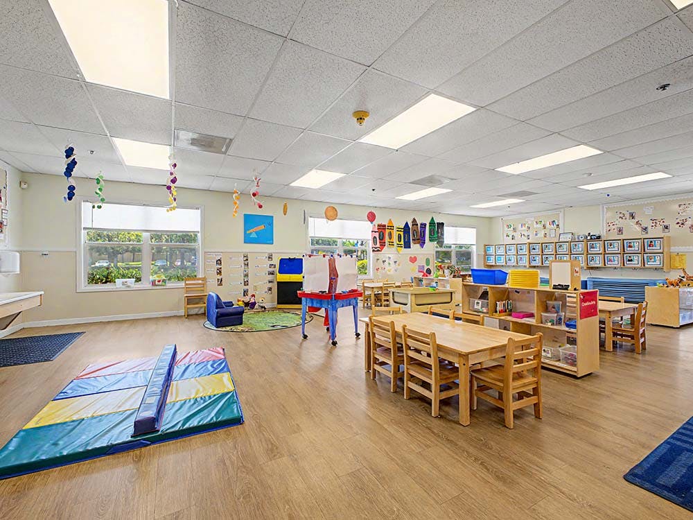 An empty early childhood classroom with small tables and chairs