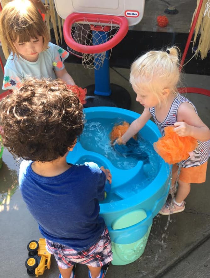 Three children playing with a water table