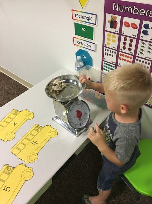 Child playing with a scale on a table
