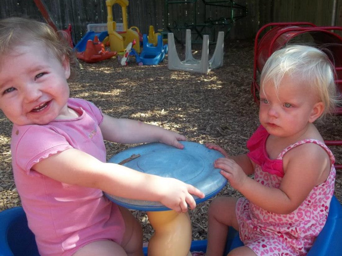 Two children playing with a blue toy in a playground