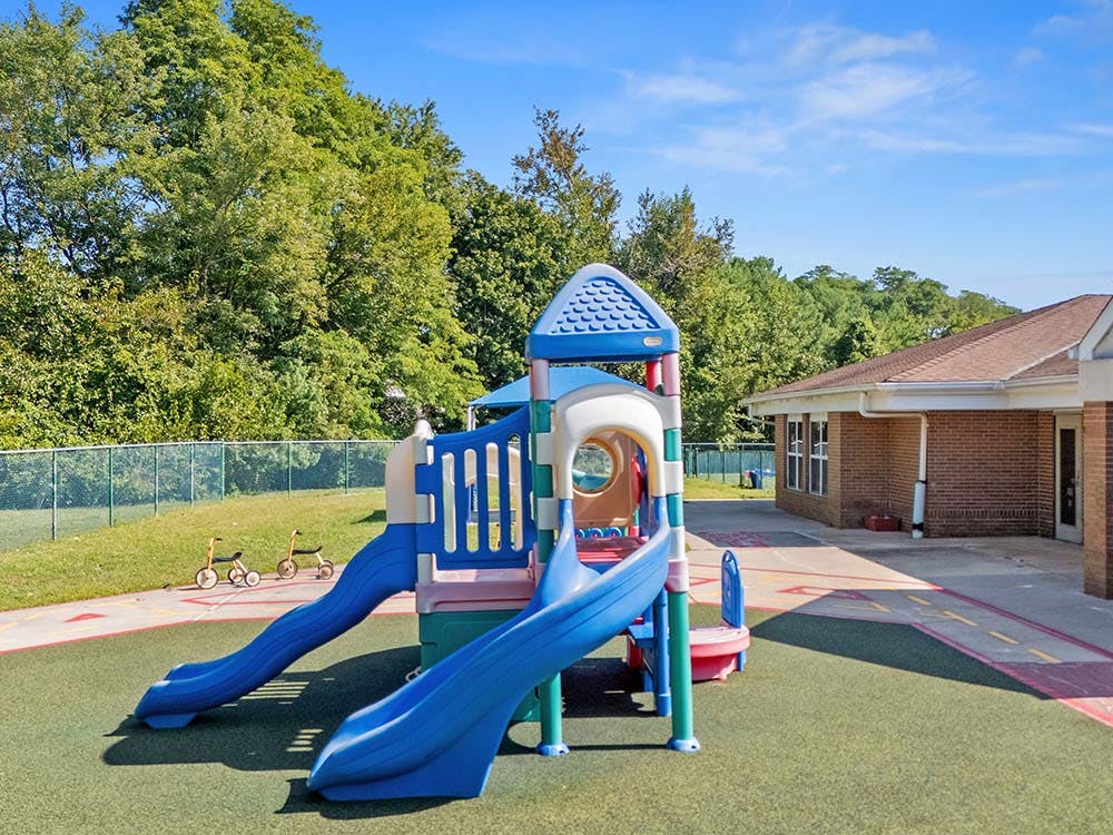 Colorful playground with multiple slides next to a brick building