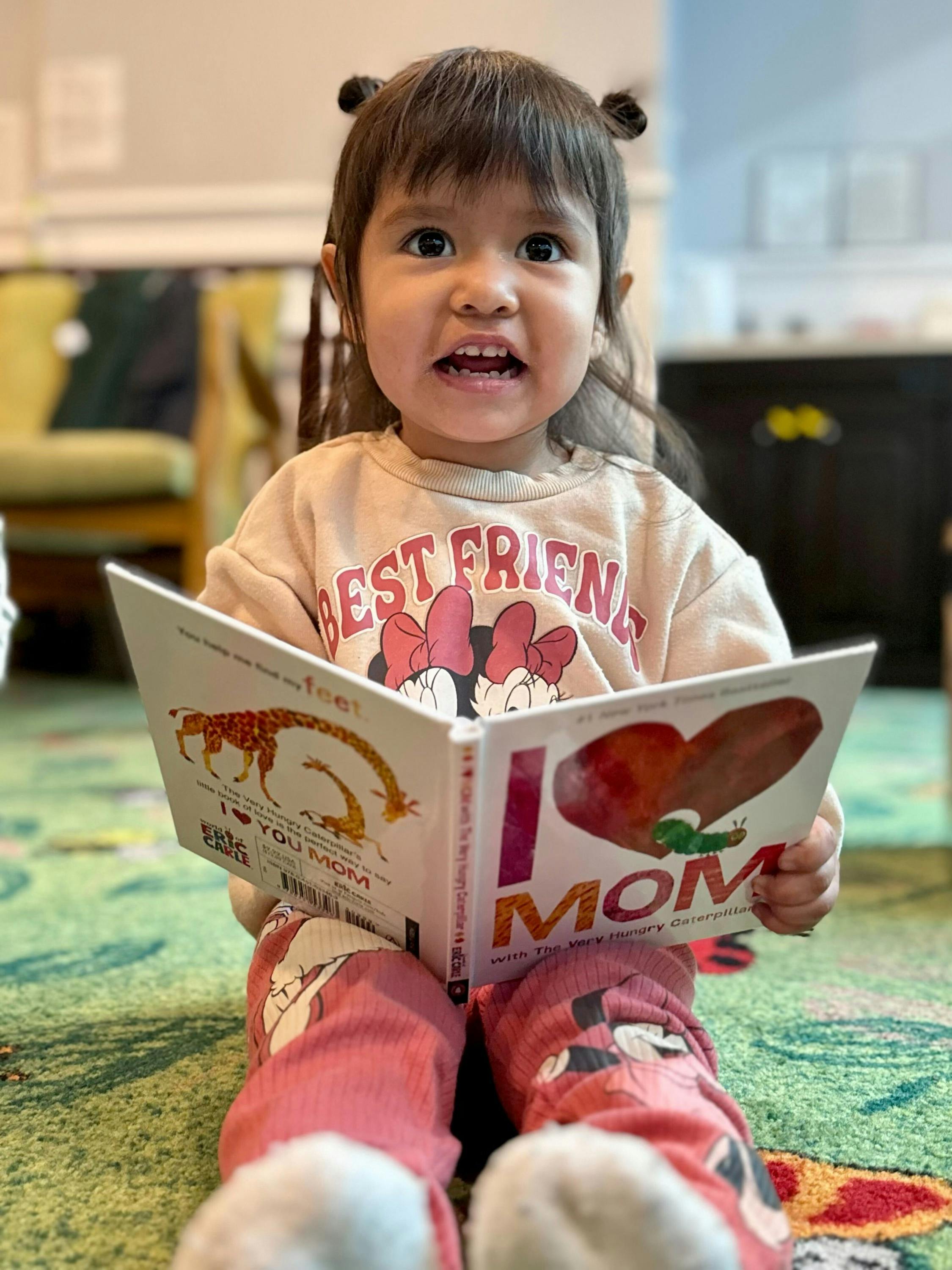 Child sitting on the floor holding an open book