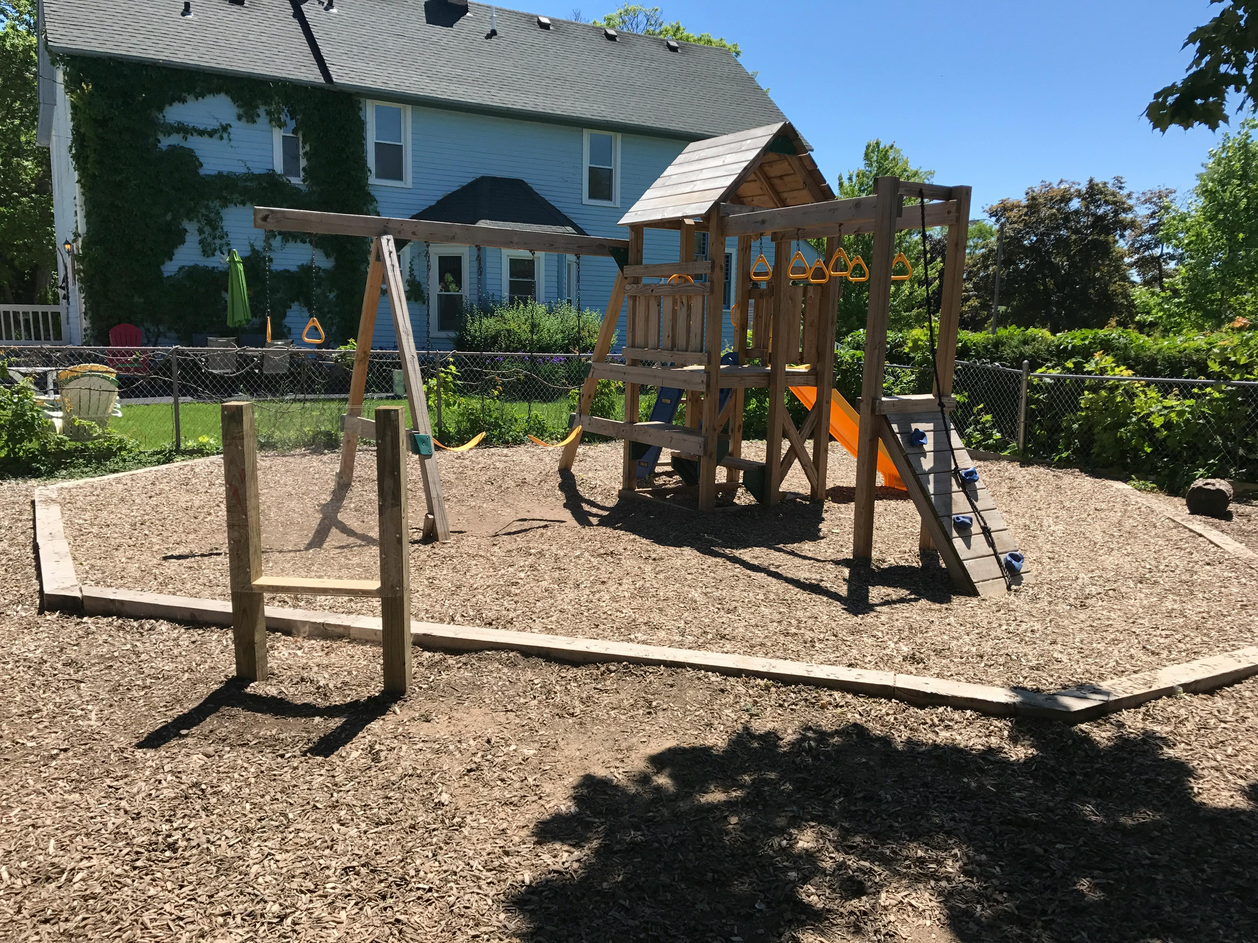 Wooden playground set with swings and slide in a backyard