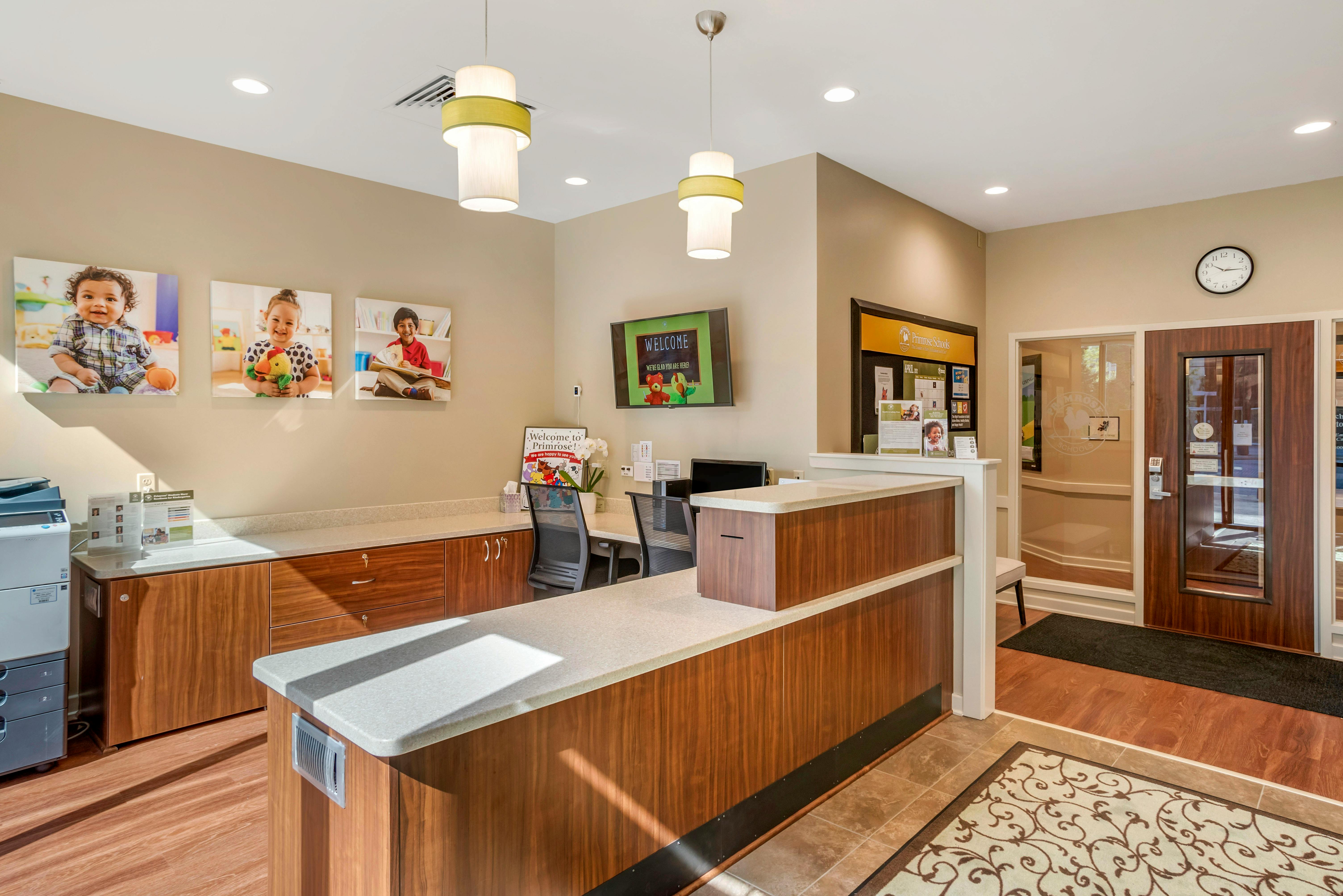 Reception desk with counters and a welcome sign, pictures of children on wall