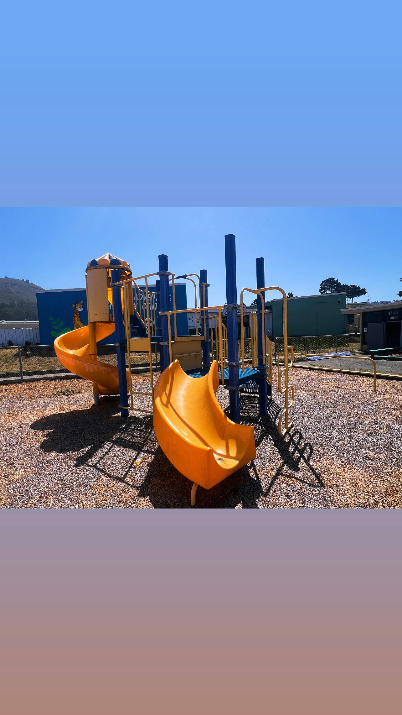 Empty yellow and blue playground structure on wood chips