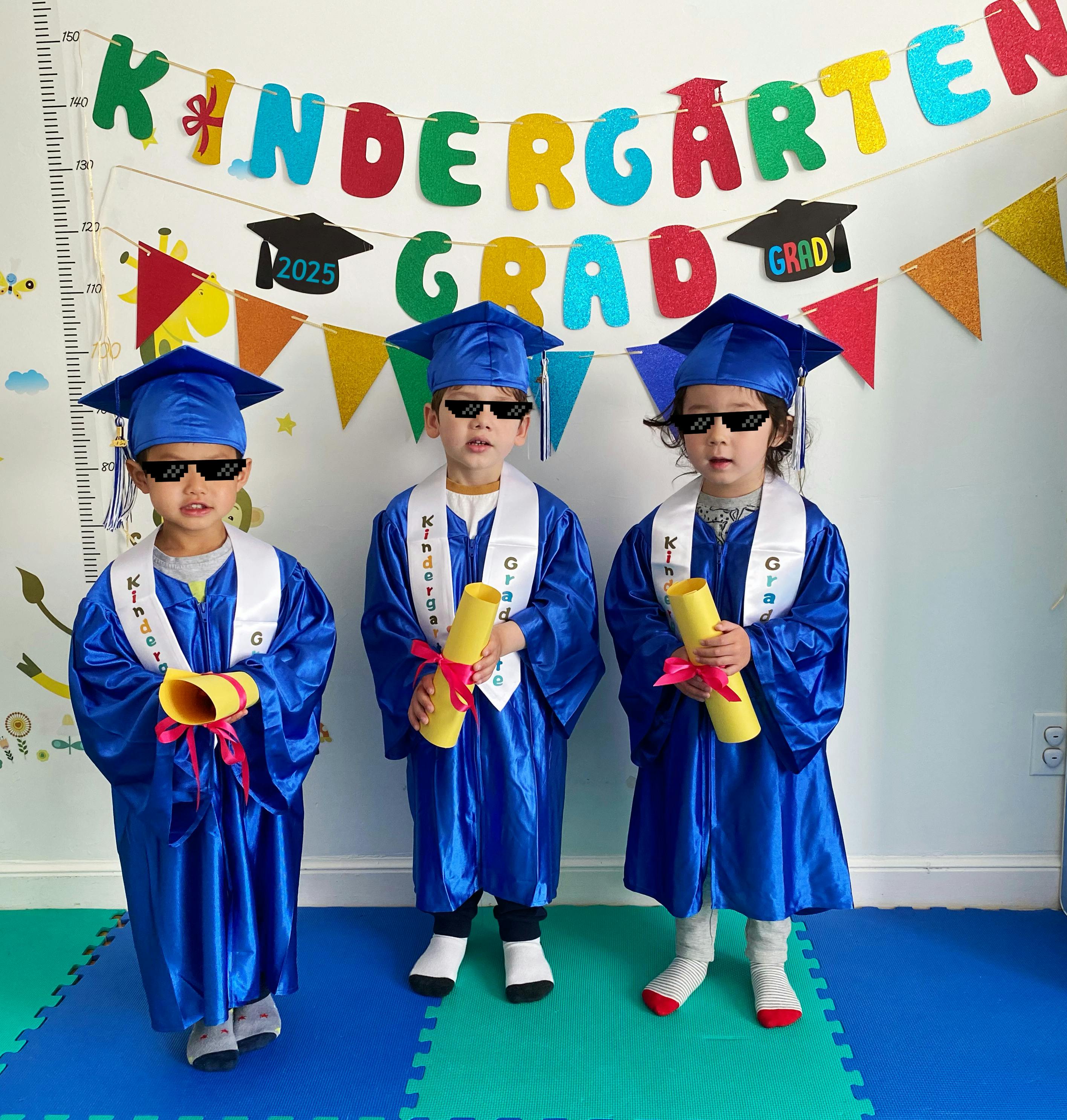 Three children in blue graduation gowns and caps holding diplomas