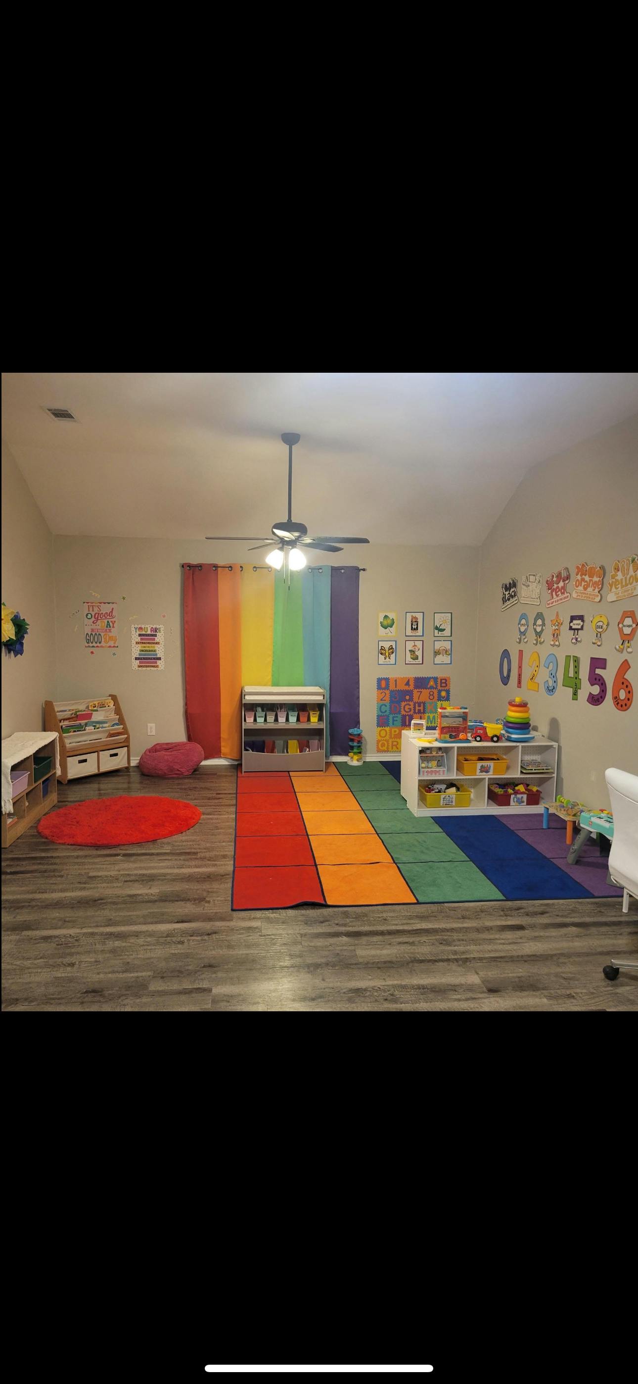 A classroom with rainbow-colored rugs, curtains, and educational decorations