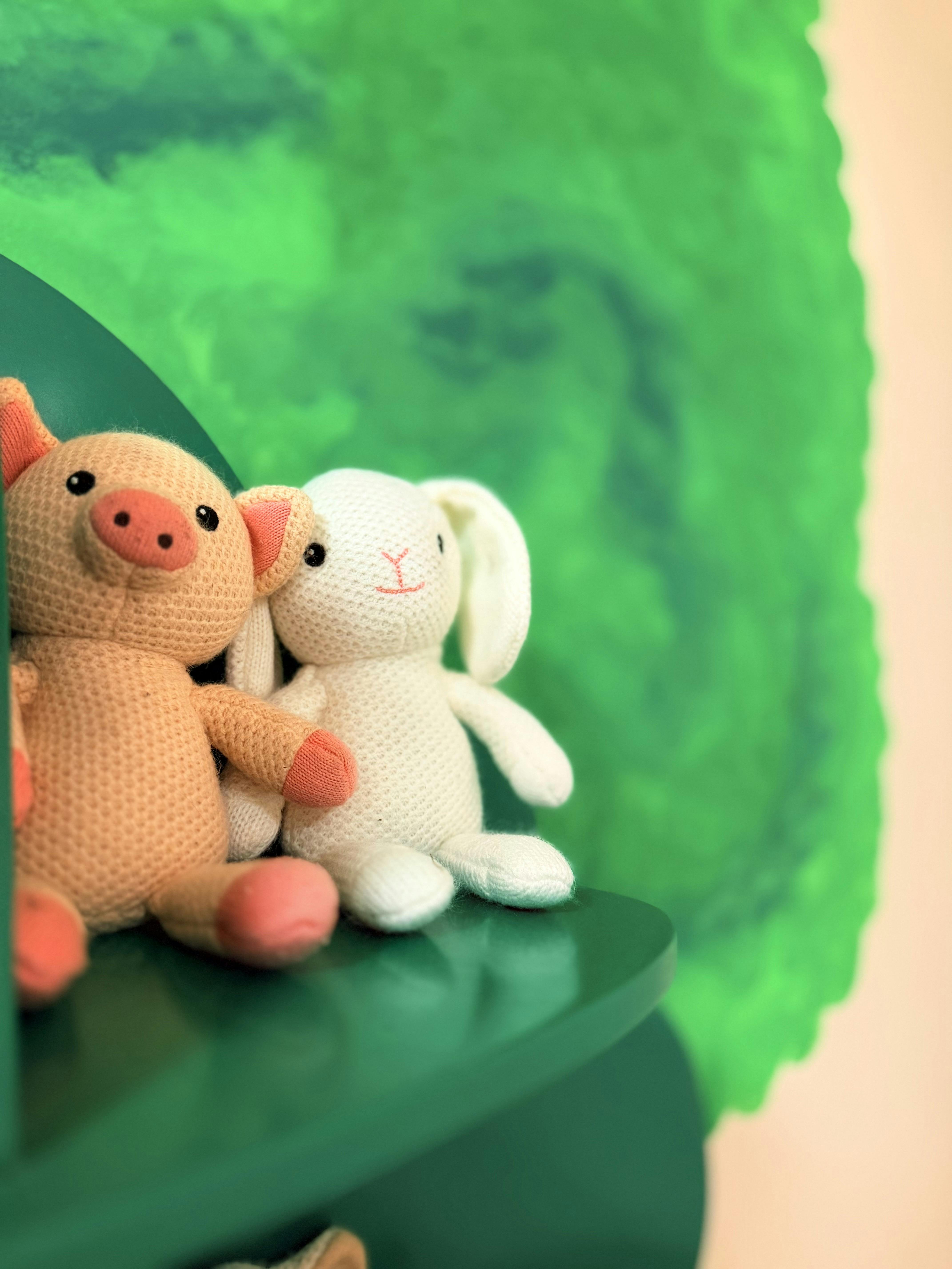 Knitted pig and rabbit plush toys sitting on a shelf