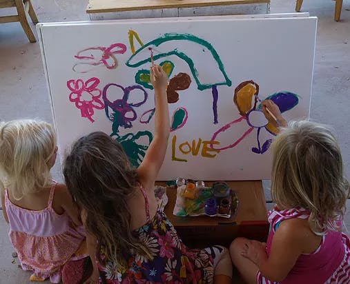 Three children painting on an easel