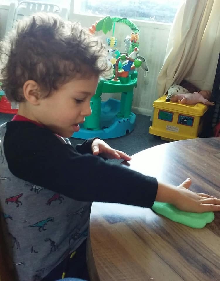 Child playing with green dough on a table