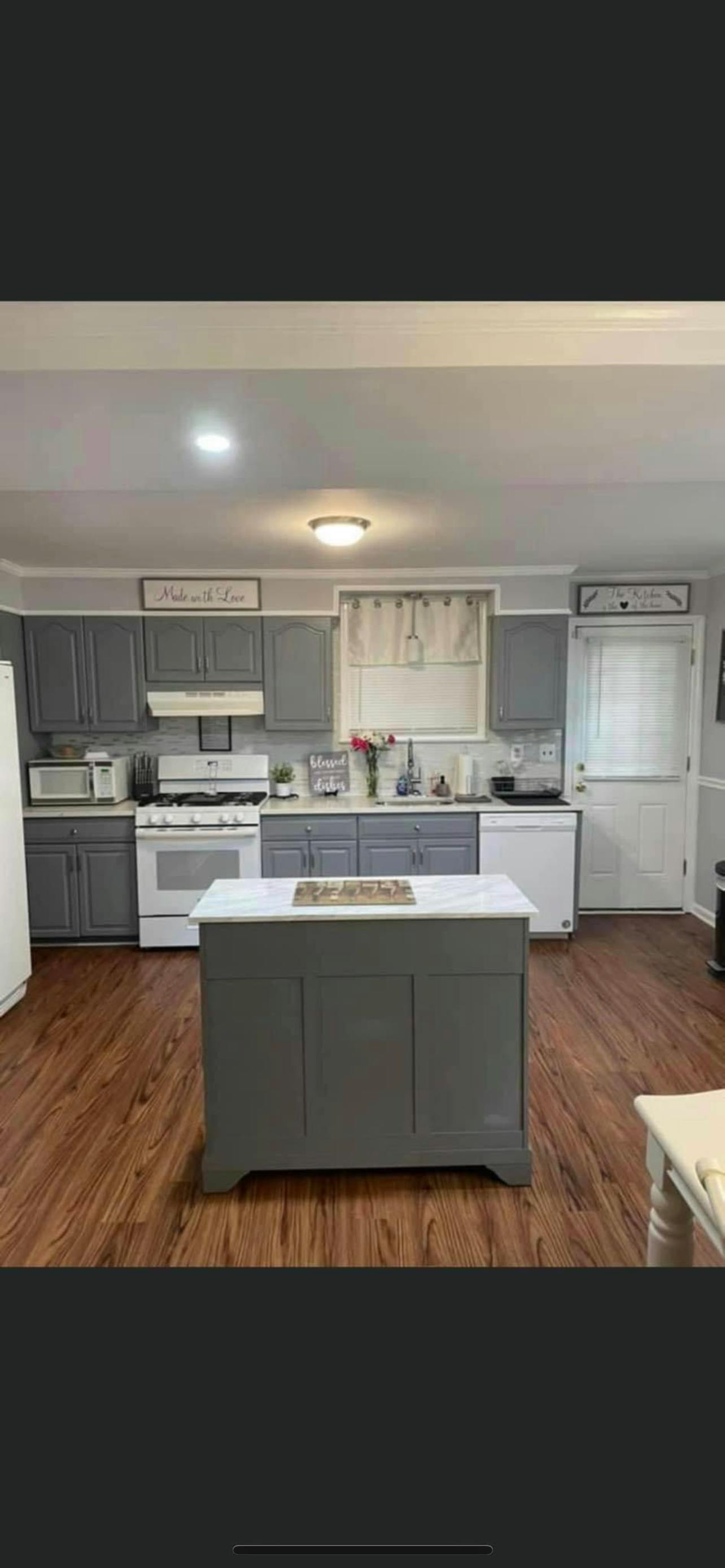 Kitchen with gray cabinets, white appliances, and a gray island
